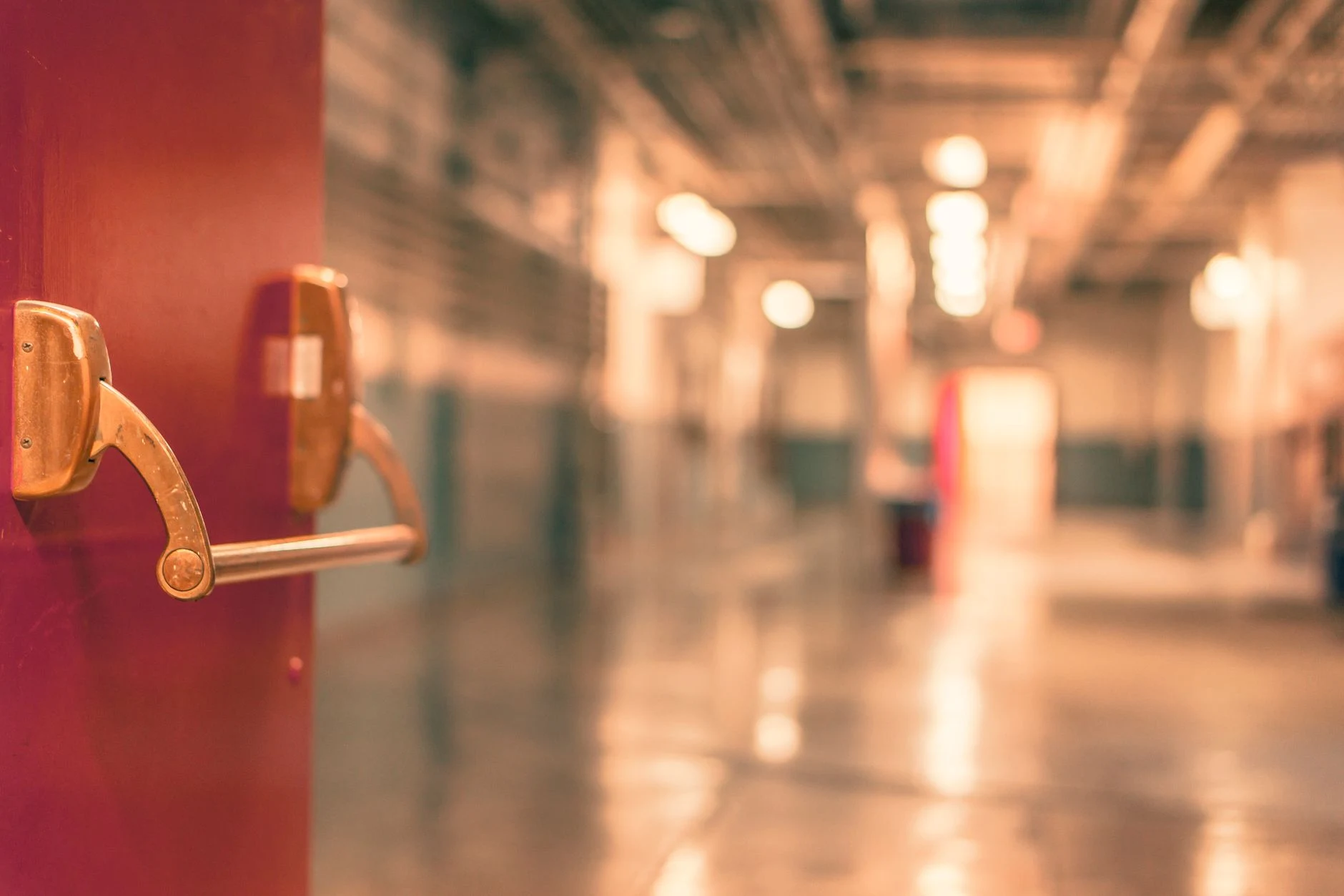 Abstract image of a blurred industrial corridor with focus on a red door handle.