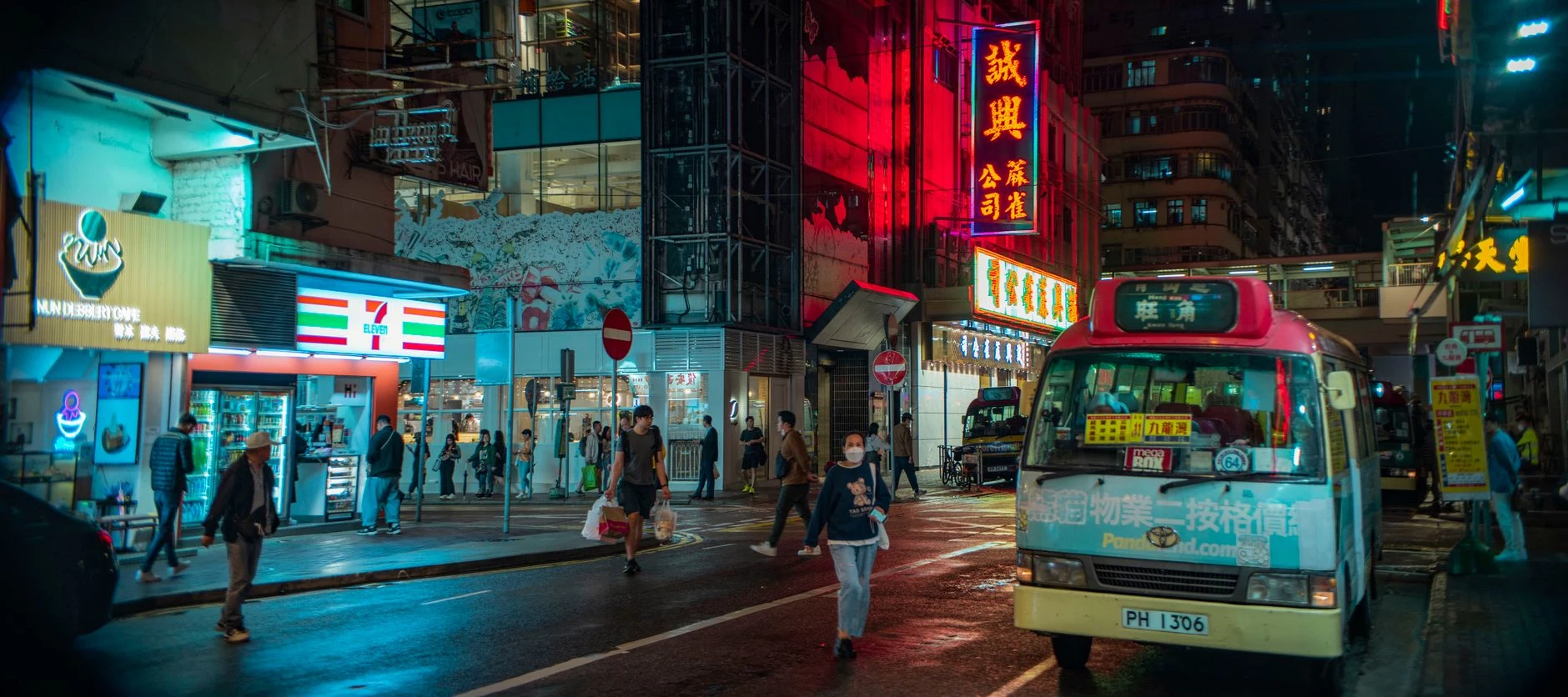 Vibrant Hong Kong street scene with neon lights, pedestrians, and a minibus at night.