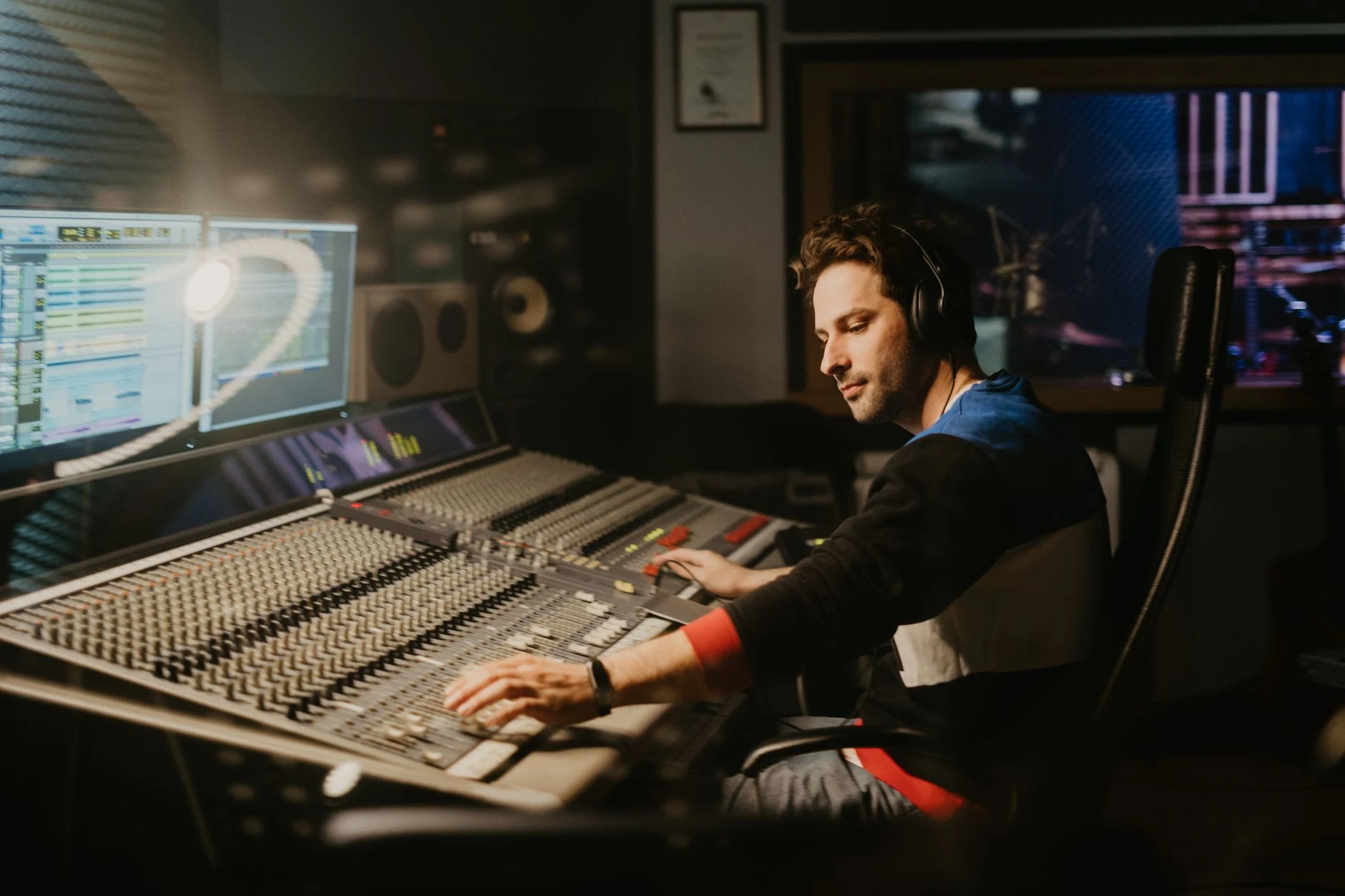 Sound engineer at a mixing console in a professional music recording studio.
