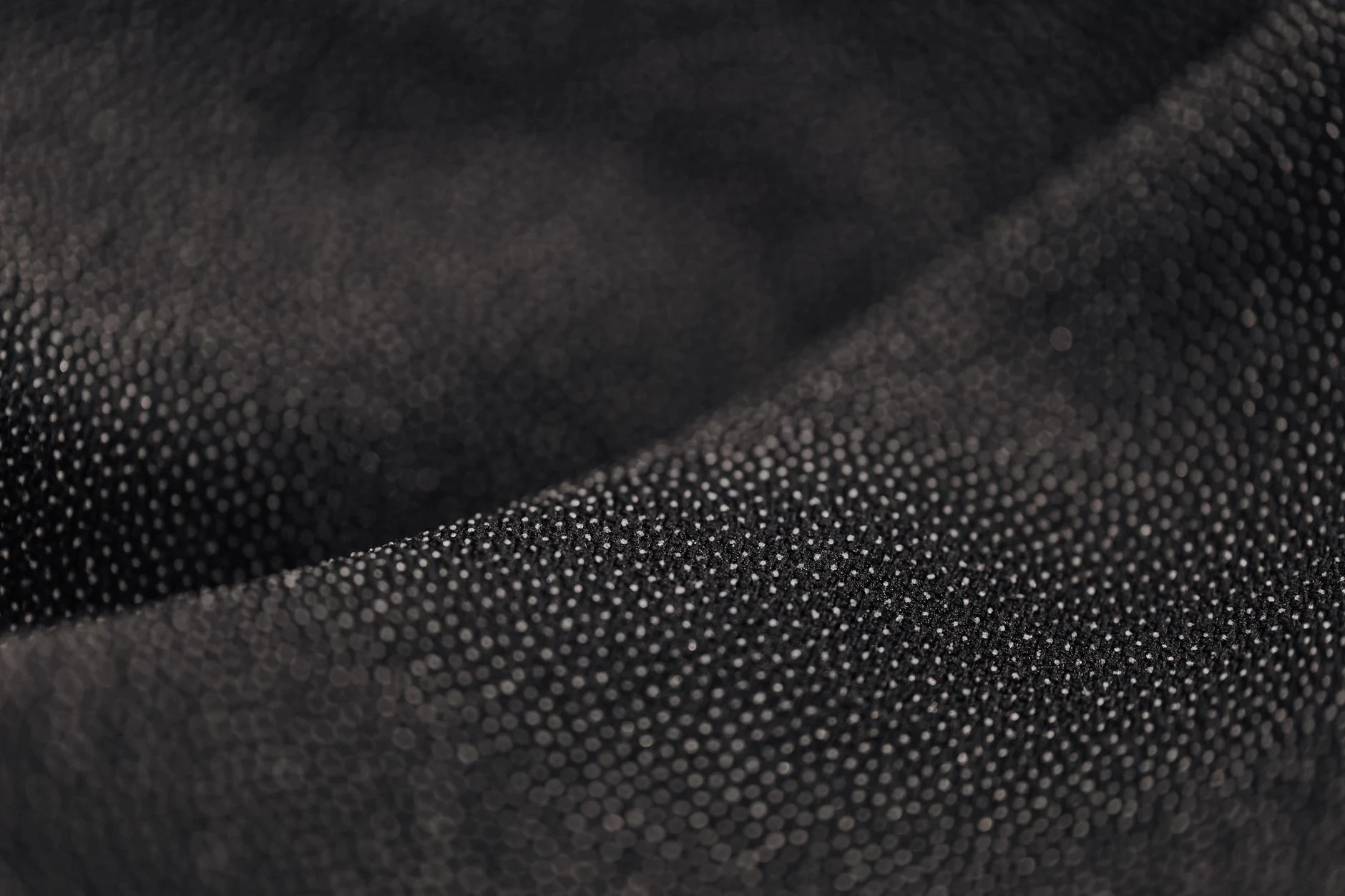 Macro shot of a black dotted fabric texture, showcasing intricate material details.