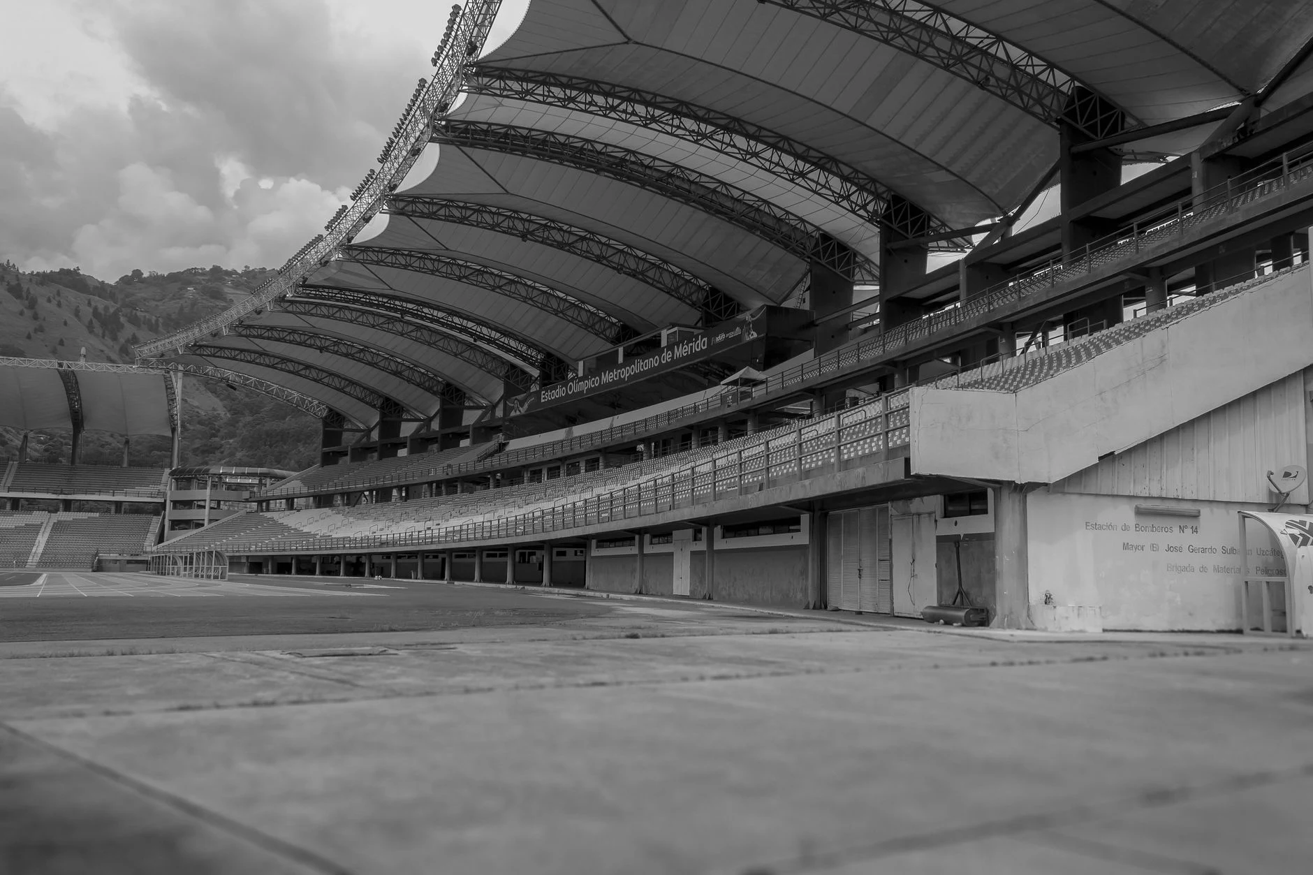 Monochrome view of an empty football stadium featuring modern architecture and expansive seating.