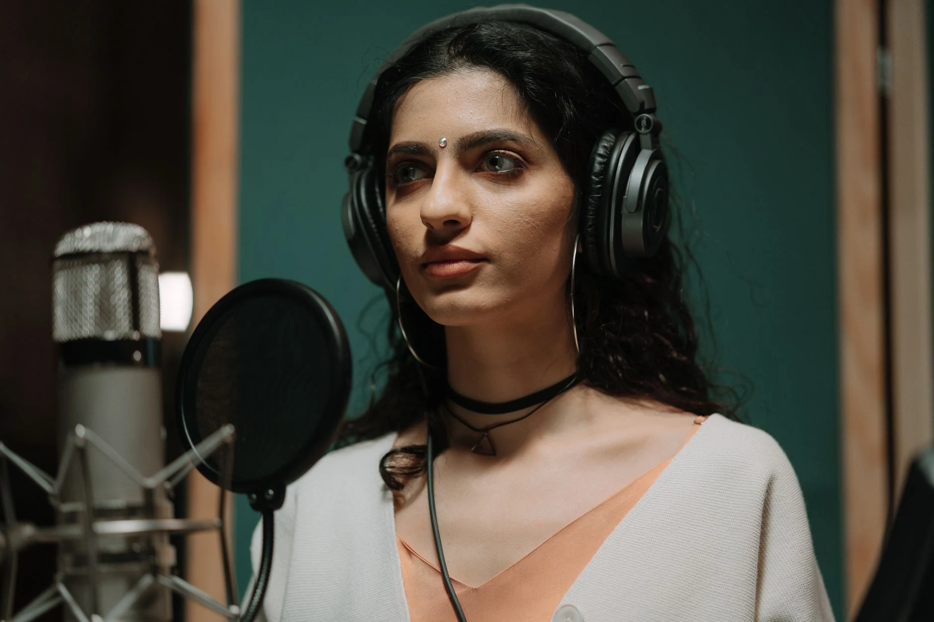 Female singer recording vocals in a professional music studio wearing headphones.