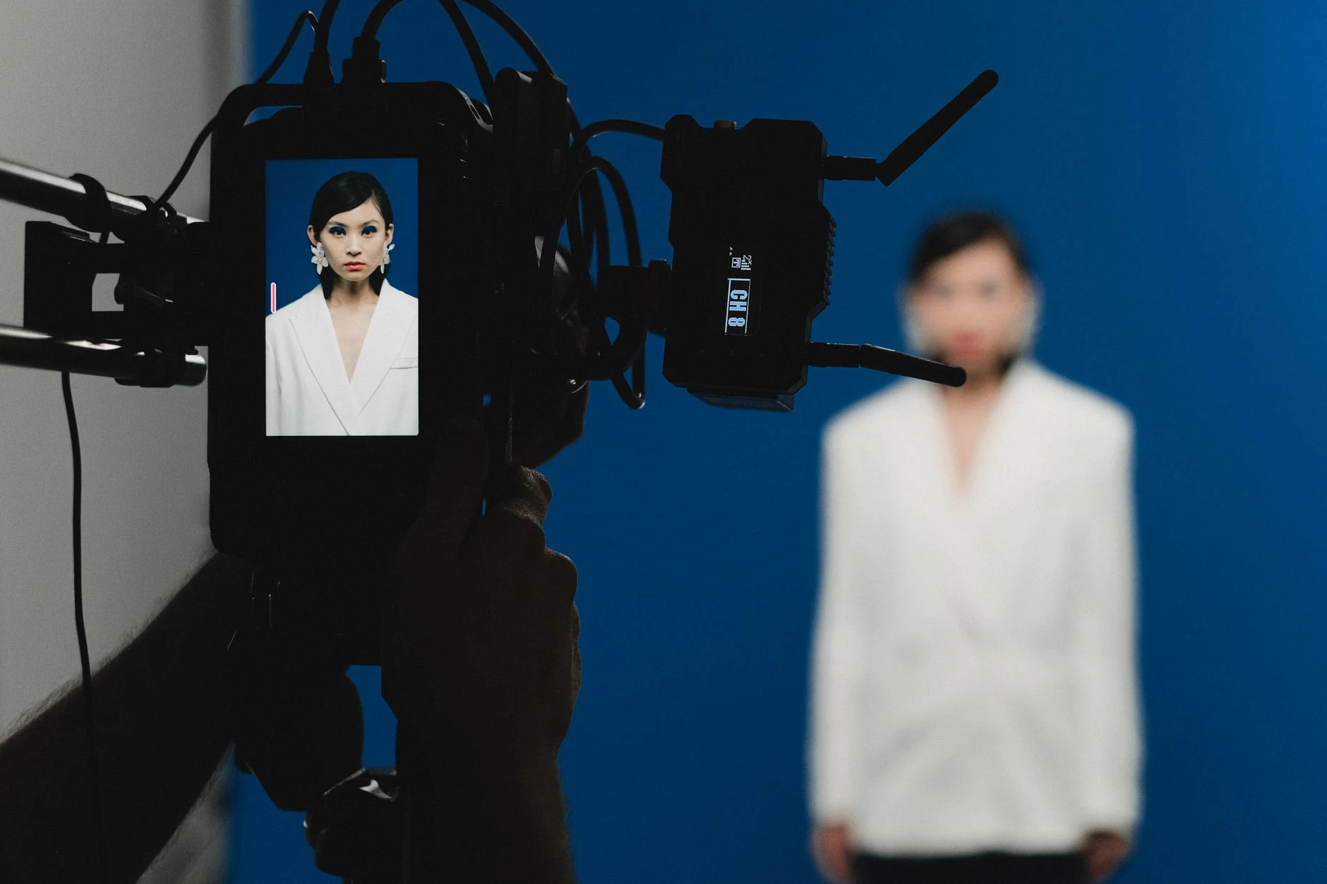 A behind-the-scenes view of a studio photoshoot featuring a woman in a white suit.