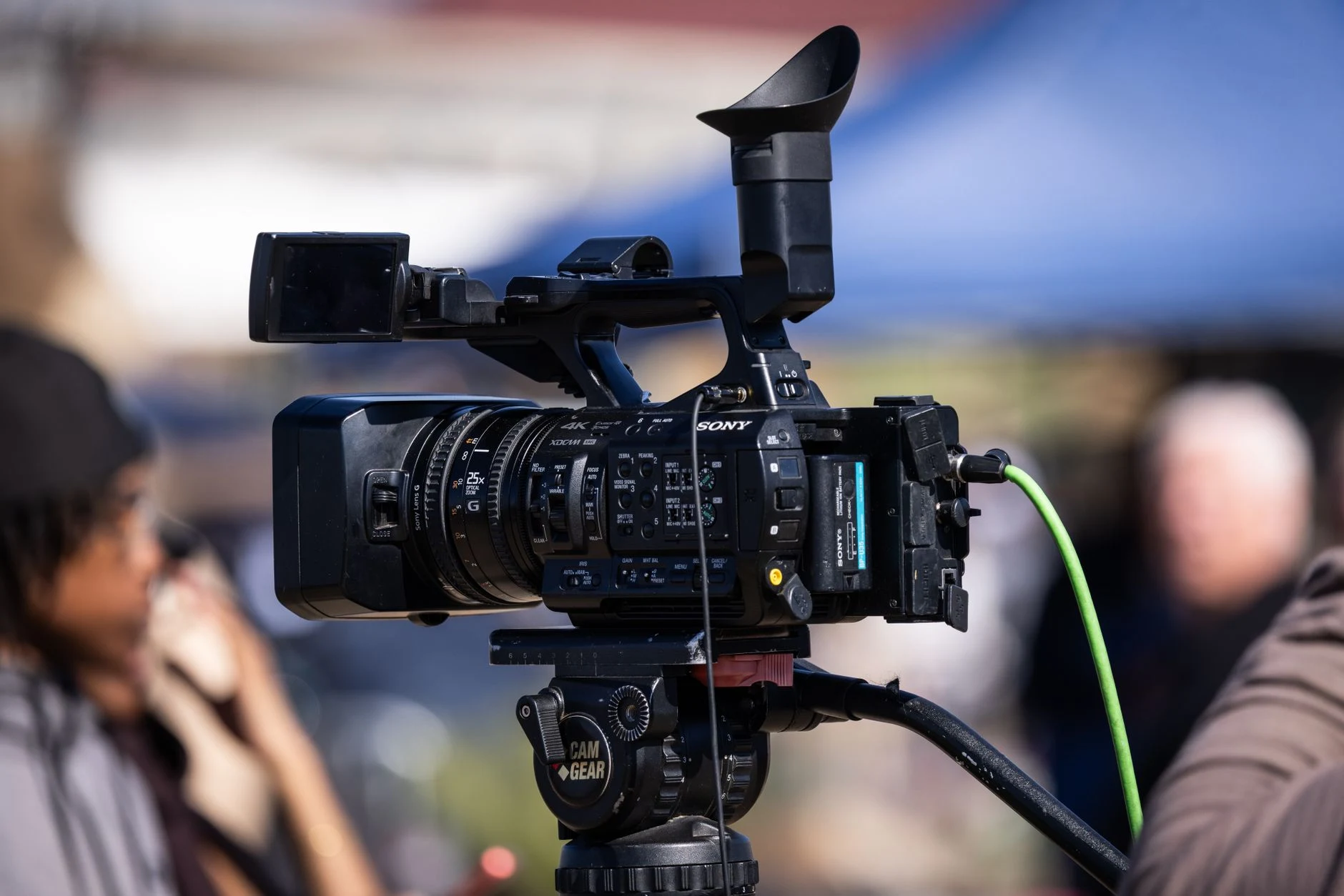 Close-up of a professional video camera set up for filming outdoors, capturing dynamic scenes in natural light.
