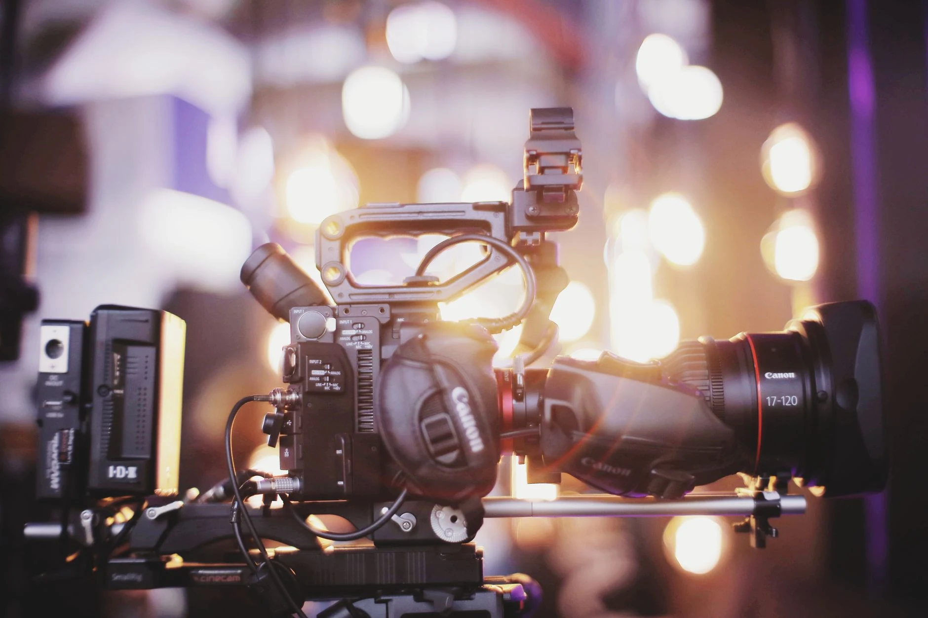 Close-up of professional video camera setup for studio filming with blurred lights in the background.
