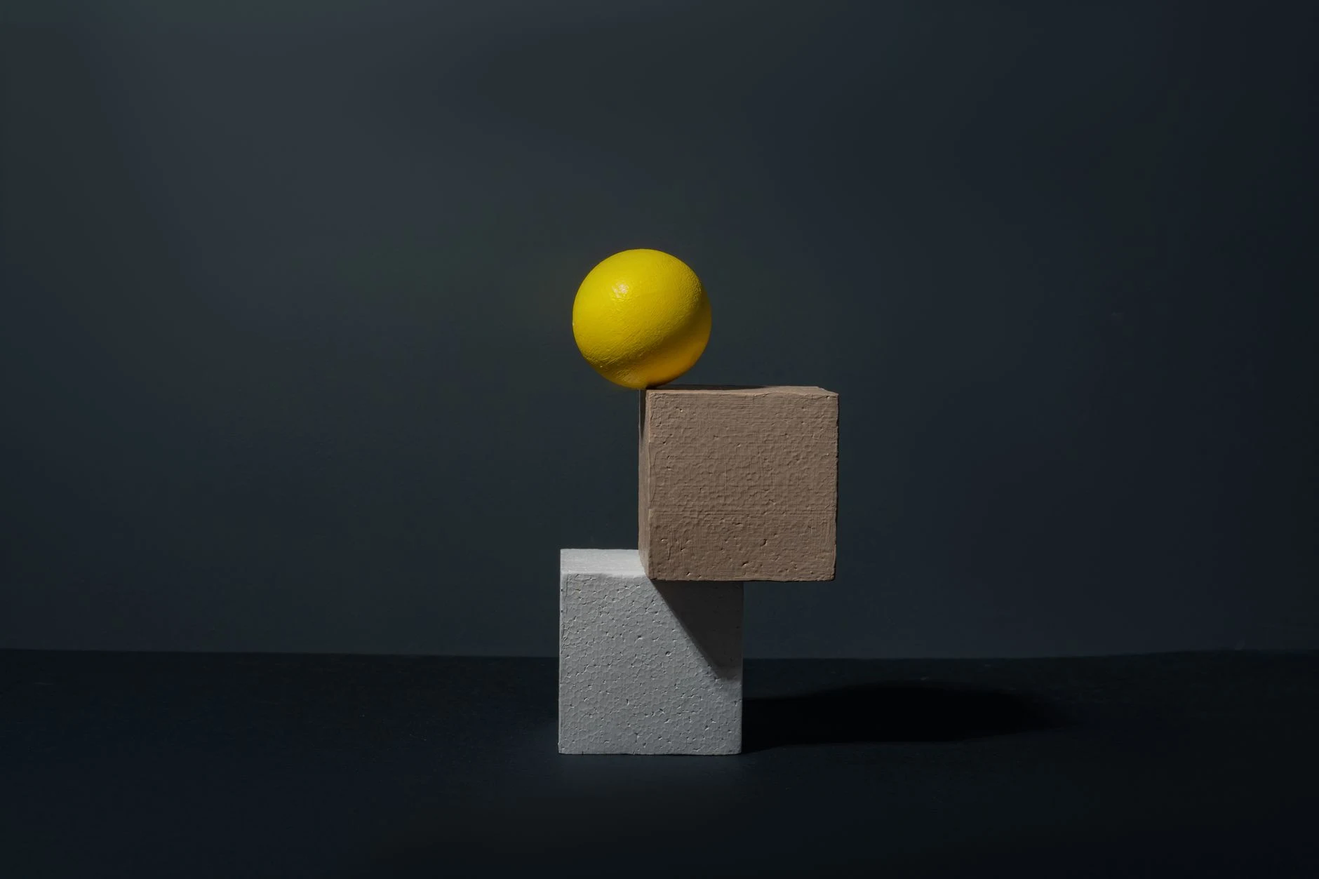 Creative composition featuring a yellow sphere and blocks in a minimalist still life setup.