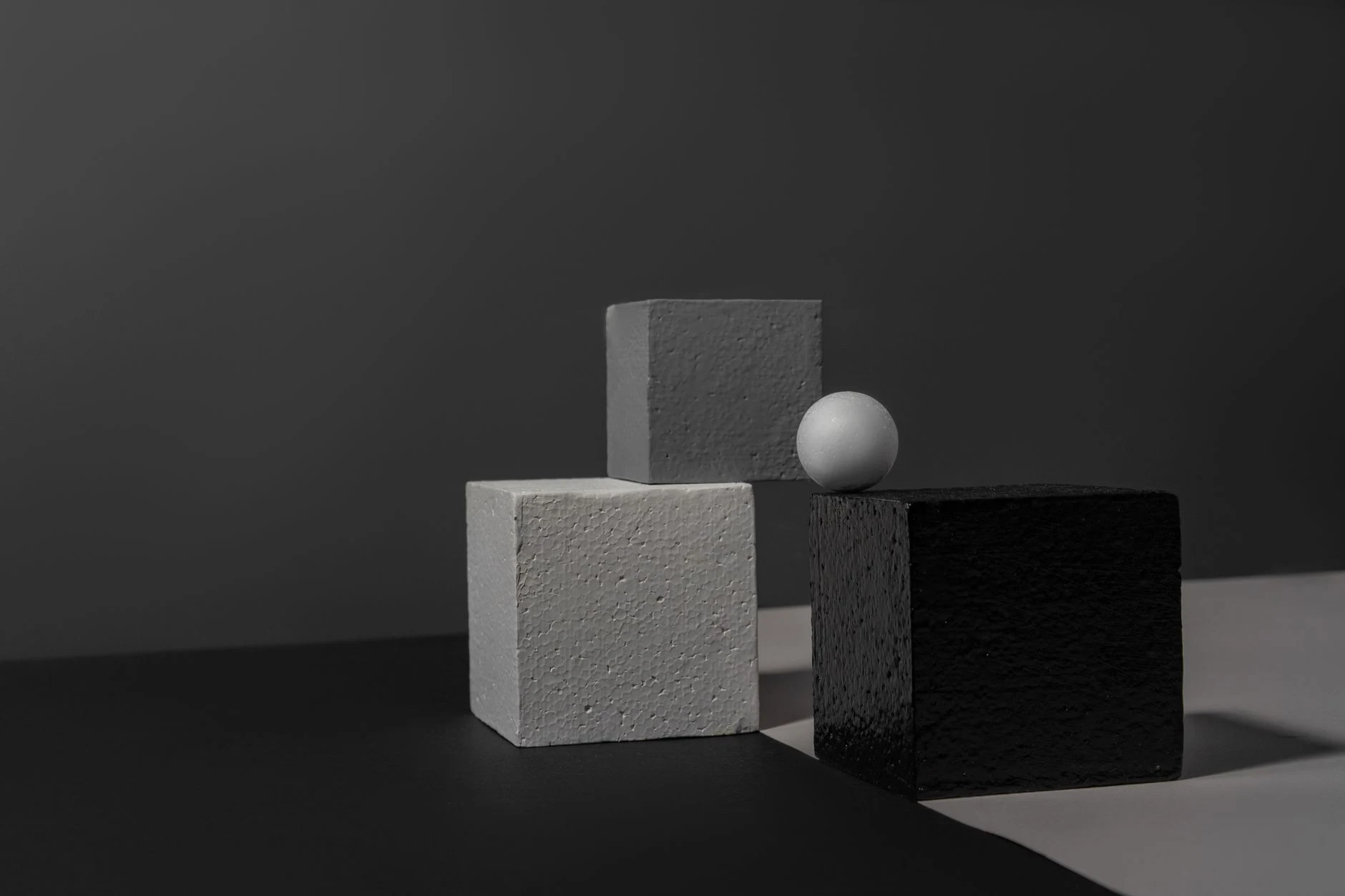 Abstract still life featuring gray geometric shapes in a studio setting.