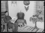 Spanish-American farmer reading in living room of his home. Chamisal, New Mexico