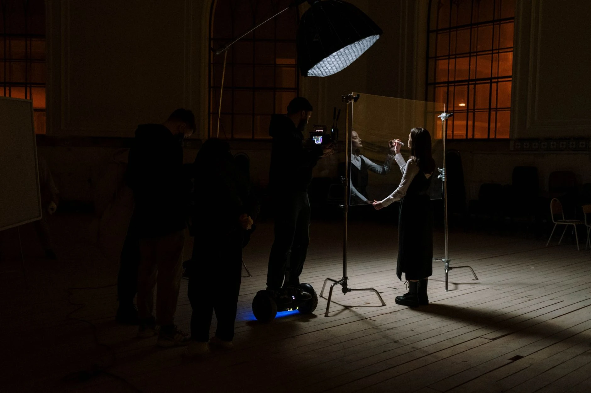 A film crew captures a performer during a dramatic indoor scene with professional lighting.